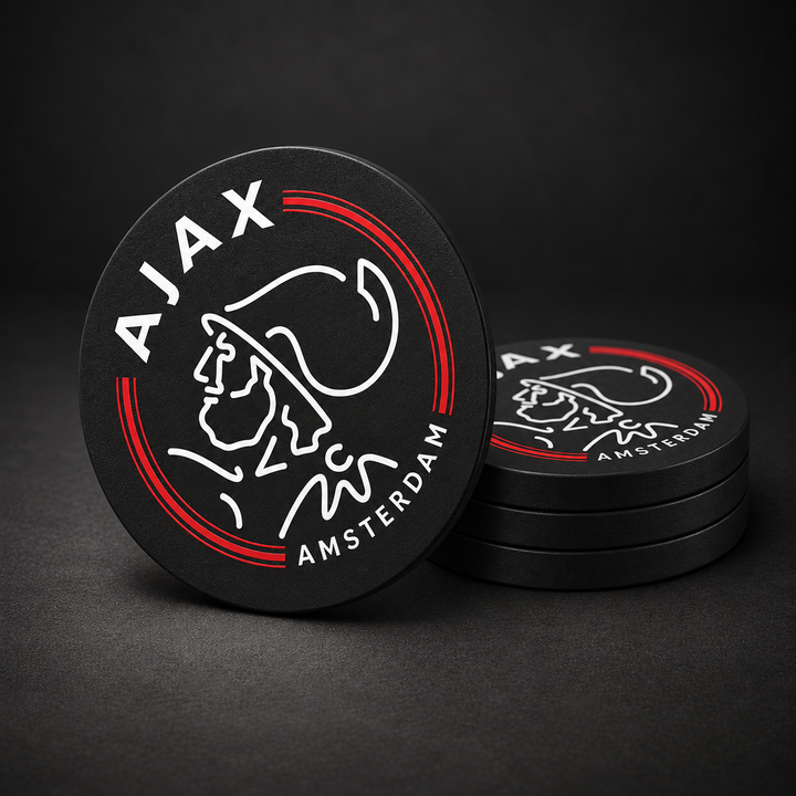 Ajax Amsterdam Drink Coasters with black sides, three stacked and one standing on a dark charcoal background