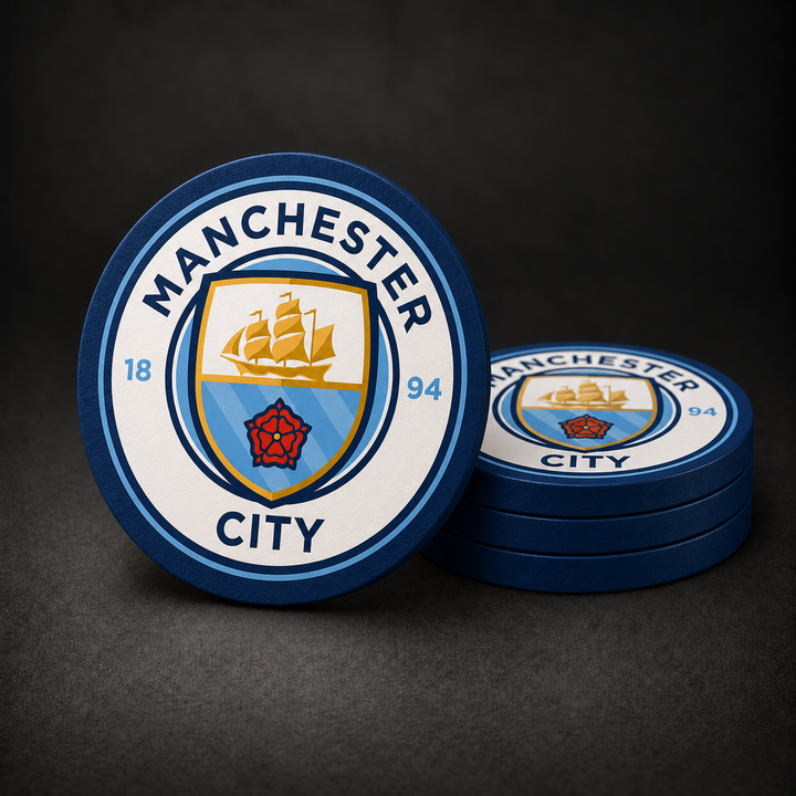 Manchester City Drink Coasters with navy blue sides, three stacked and one standing on a dark charcoal background