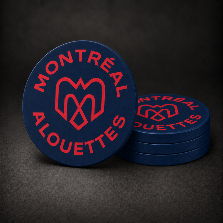 Montreal Alouettes Drink Coasters with navy blue sides, three stacked and one standing on a dark charcoal background
