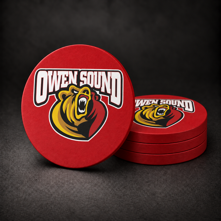 Owen Sound Attack Drink Coasters with red sides, three stacked and one standing on a dark charcoal background