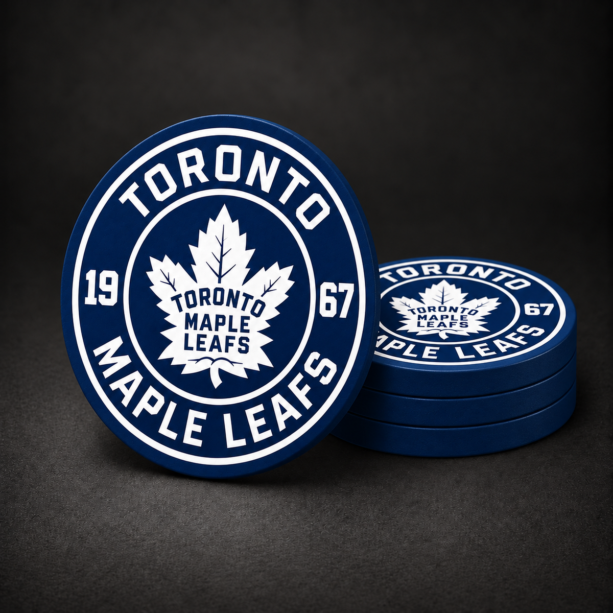 Toronto Maple Leafs drink coasters with navy blue sides, three stacked and one standing on a dark charcoal background
